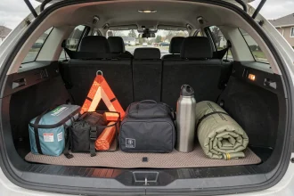 Coffre de voiture bien organisé avec les accessoires indispensables pour voyager sereinement : trousse de secours, triangle de signalisation, organisateur de voyage et couverture de secours