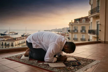 Homme musulman effectuant la prière du soir sur un balcon avec vue sur le port de Marseille en été